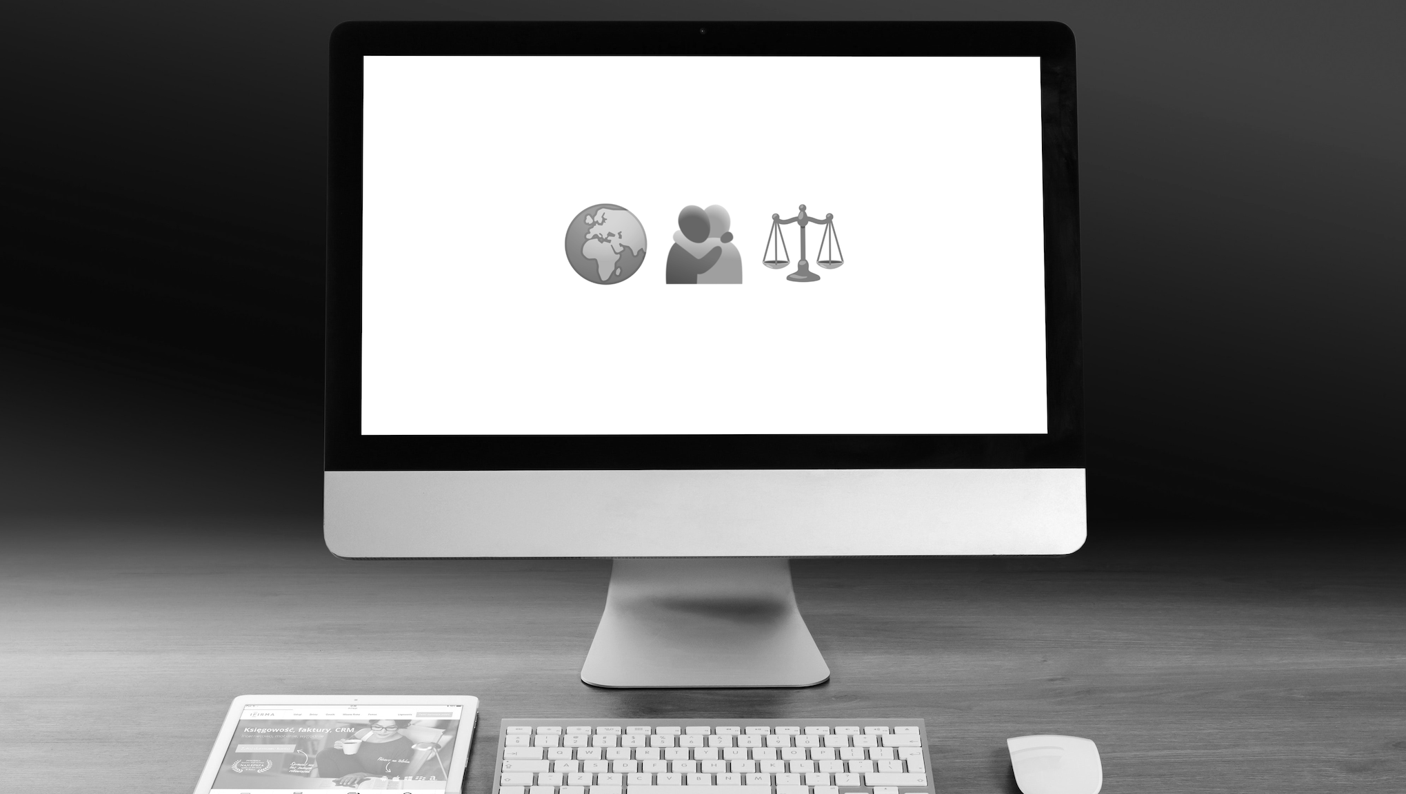 Bild von einem Desktop-Monitor, davor Keyboard, Maus und Tablet. Auf dem Bildschirm sind drei Emojis zu sehen, die die ESGs symbolisieren sollen: Weltkugel, sich umarmende Menschen, Waage.